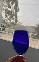 A hand holding a blue wine glass.