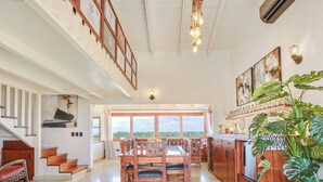 Un vaste espace de salle à manger aménagé avec du mobilier en bois, une cuisine dotée d’un plan de travail en bois et une grande fenêtre offrant une vue sur l’extérieur.