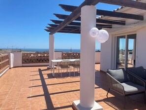 Una terrazza con tavolo e sedie, un divano e vista mare.