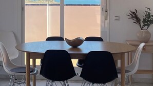 A dining area with a table and chairs, a hanging light fixture, and a view of the sea through a glass door. - Penthouse with exceptionel sea, mountain and golf view over Miraflores golf (AN)
