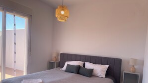 A modern bedroom with a large bed, two bedside tables with lamps, a hanging light fixture, and a view through a sliding door. - Penthouse with exceptionel sea, mountain and golf view over Miraflores golf (AN)