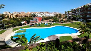 A swimming pool with lounge chairs and umbrellas, surrounded by greenery and buildings in the background. - Penthouse with exceptionel sea, mountain and golf view over Miraflores golf (AN)