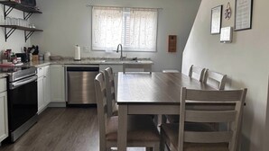 Eine kompakte Küche mit Essbereich, ausgestattet mit Geschirrspüler, Backofen und einem Esstisch mit Stühlen.