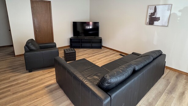 Un salon moderne avec un canapé d’angle, un téléviseur à écran plat et un plancher en bois.