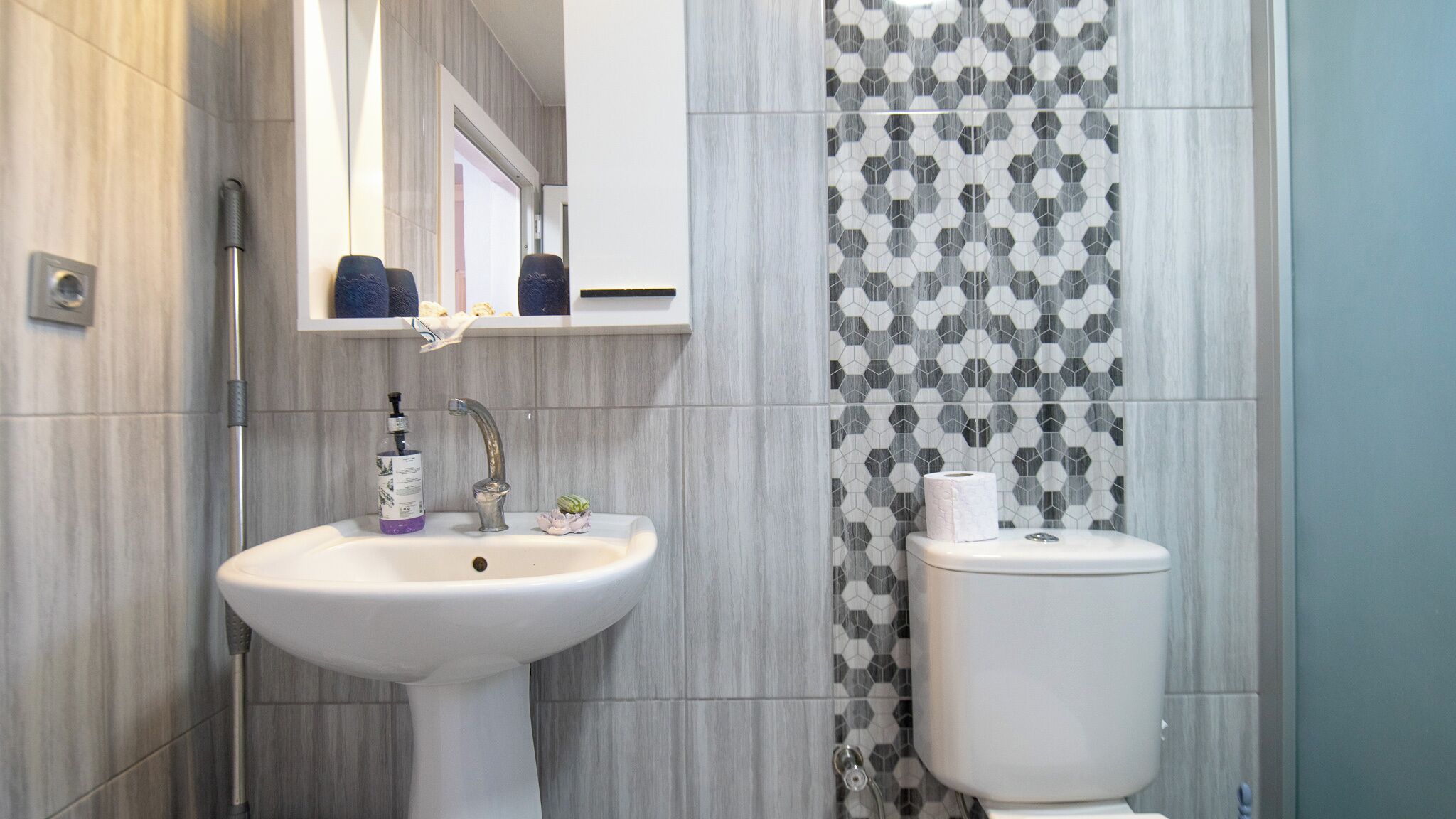 Een badkamer met een wit wastafel, een spiegel erboven en een toilet.