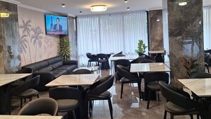 A modern restaurant with marble flooring, black upholstered seating, and a television screen on the wall. - Point Central Hotel (Addis Ababa)