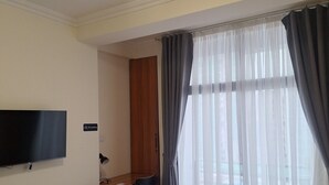 A hotel room with a bed, a desk, a chair, a television, and a window with curtains. - Point Central Hotel (Addis Ababa)