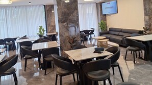 A modern restaurant with marble flooring, black upholstered chairs, and a large stone pillar. - Point Central Hotel (Addis Ababa)