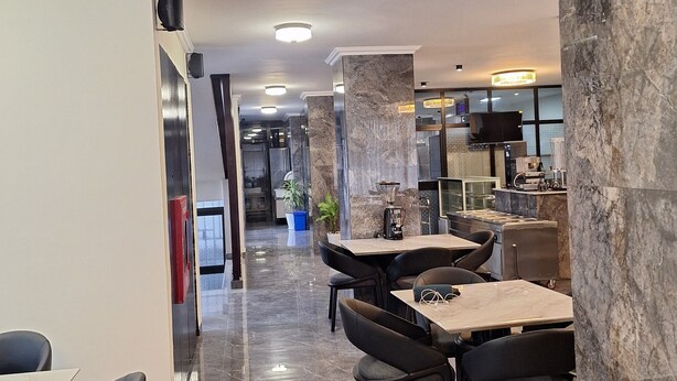 A modern dining area with marble flooring, black upholstered chairs, and a central table with a coffee machine. - Point Central Hotel (Addis Ababa)