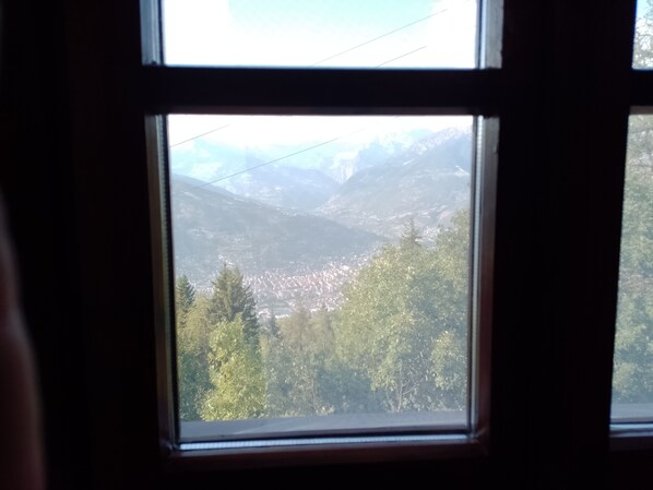 A window view of a mountainous landscape with a town below.