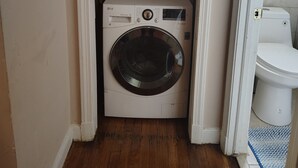 A compact laundry room with a washing machine and a toilet.