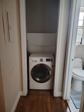 A compact laundry room with a washing machine and a toilet.