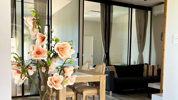 Una sala de estar moderna con comedor, ventanas amplias y una planta en maceta.