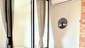 Una sala de estar moderna con un sofá gris, una pequeña mesa de centro de madera y una pieza de arte de pared con motivos de árboles decorativos.