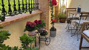Un patio con plantas en macetas, una bicicleta y mobiliario exterior.