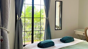 Un dormitorio con cama, escritorio y ventana con cortinas.