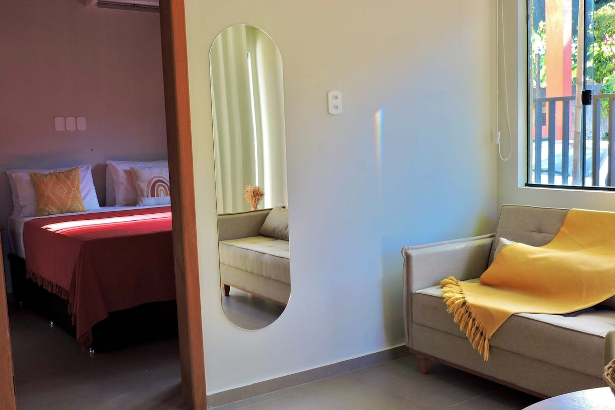 Une pièce avec un lit, un canapé, un miroir et une fenêtre.