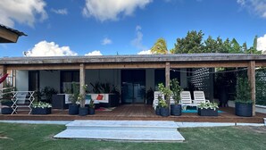 Un espace extérieur abrité, doté d’une terrasse en bois, de sièges et de plantes en pot.
