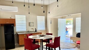 Une cuisine comprenant un coin repas, avec un réfrigérateur, un évier et une table à manger avec des chaises.