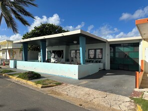 Un edificio con una zona esterna coperta per sedersi, un garage e un murale sulla parete.