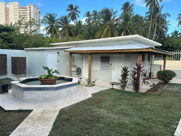 Una casa moderna con un patio coperto, una piscina e un prato curato.