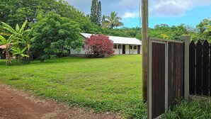 A fenced yard with a building, trees, and a clear sky. - Hare Kivi (Hanga Roa)