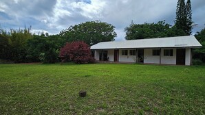 A single-story building with a flat roof, surrounded by a well-maintained lawn and various trees. - Hare Kivi (Hanga Roa)