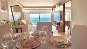 Un área de comedor con vista al mar, un sofá y una mesa de comedor con platos y vasos.