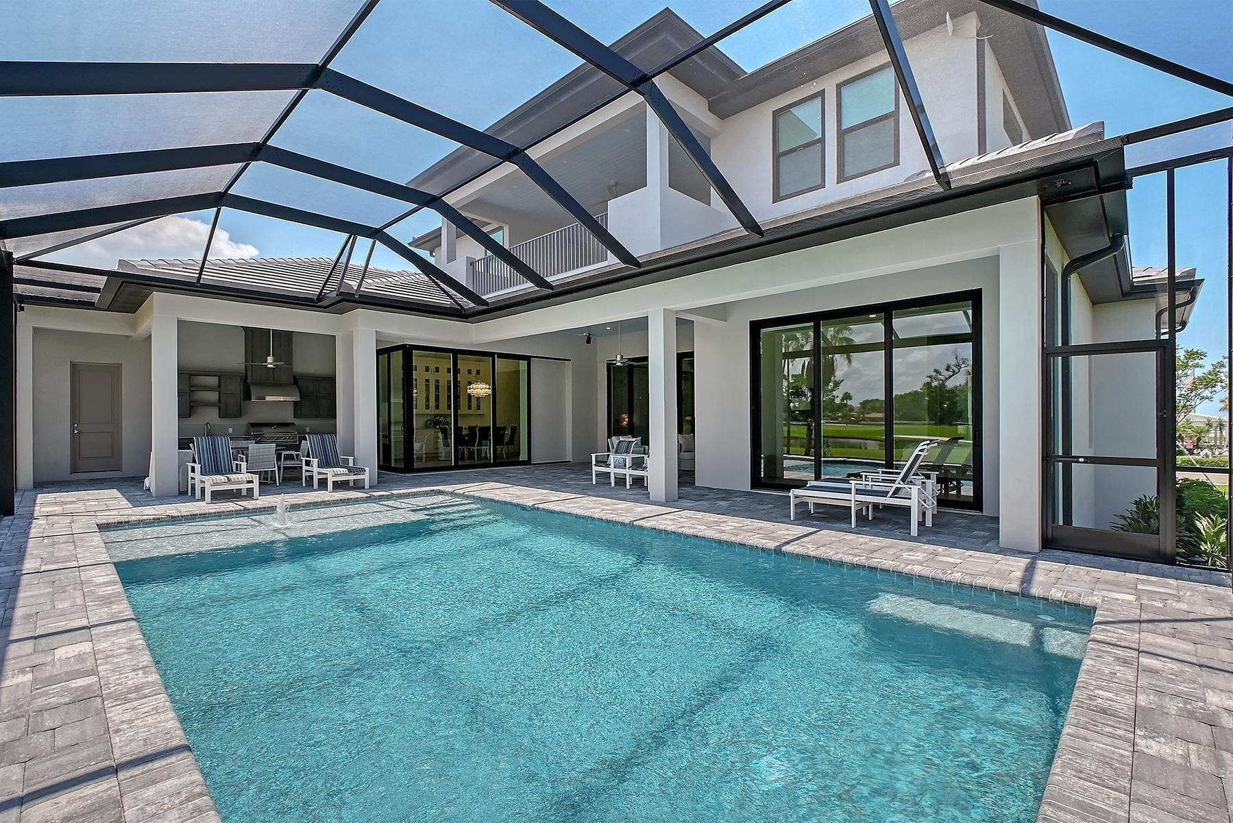 A modern house with a swimming pool, outdoor seating, and large windows.