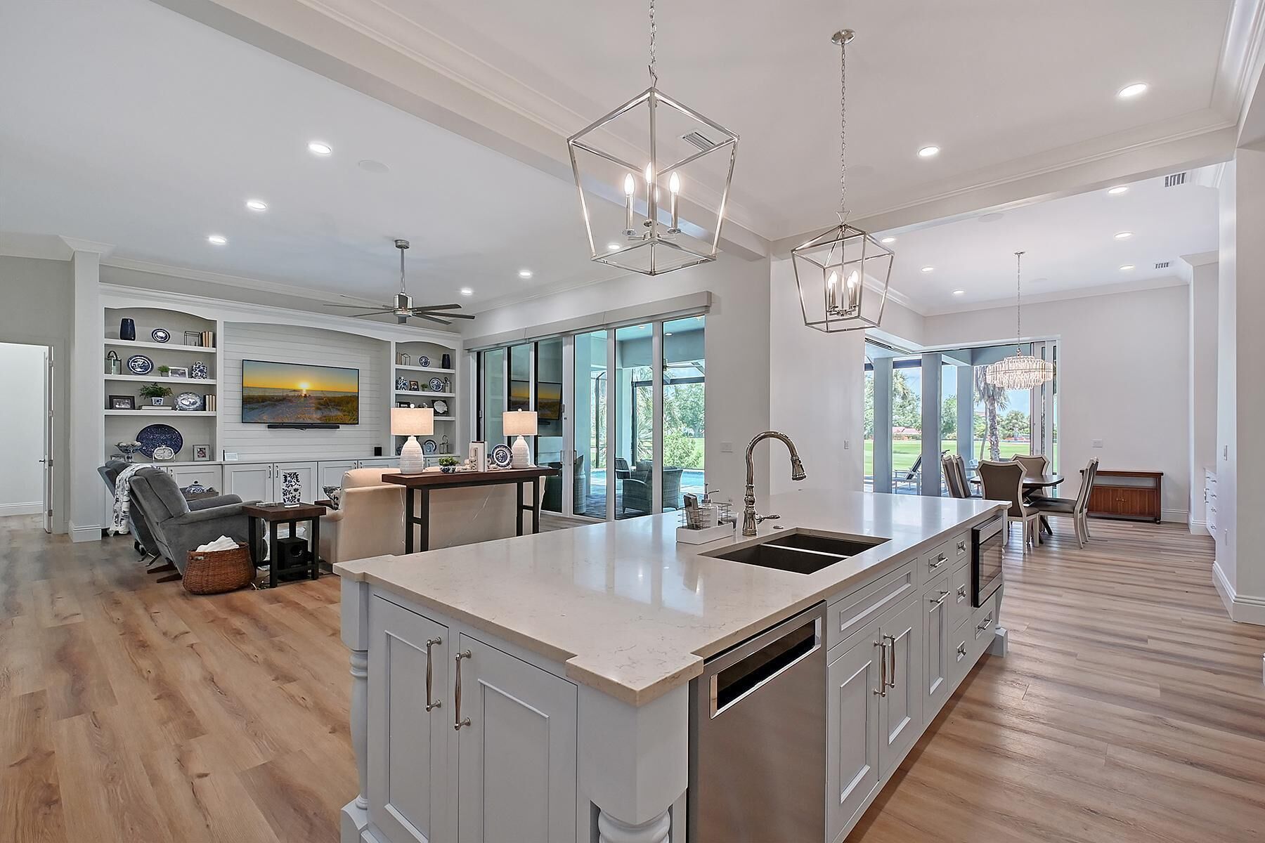 A spacious kitchen with a large island, modern pendant lights, and a view to the outdoor patio.