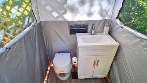 Une petite salle de bain fermée, comprenant des toilettes, un lavabo et un meuble de rangement.