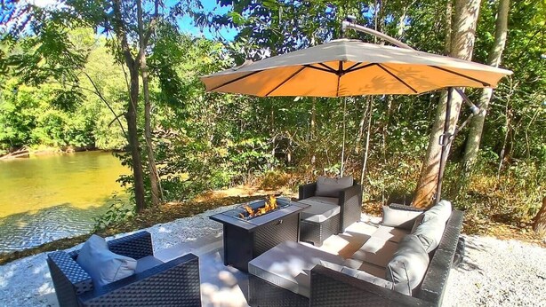Un espace extérieur aménagé avec un foyer, des fauteuils confortables et un grand parasol.
