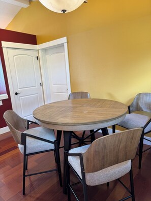 Un comedor con una mesa redonda y seis sillas, una puerta blanca y una pared amarilla.