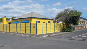 A yellow building with blue accents, a gated entrance, and a sign indicating '86 on Cook'.