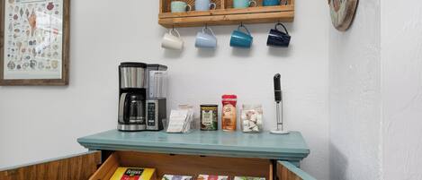 A coffee bar area with a coffee machine, mugs, and various coffee products.