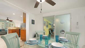A dining area with a glass table, blue plates, and matching chairs. - Sunshine Paradise Minutes From Action. Grill, Bikes, Beach Gear & More Included! (Cape Coral)