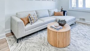 Een moderne woonkamer met een bank, salontafel en ingelijste foto's aan de muur.