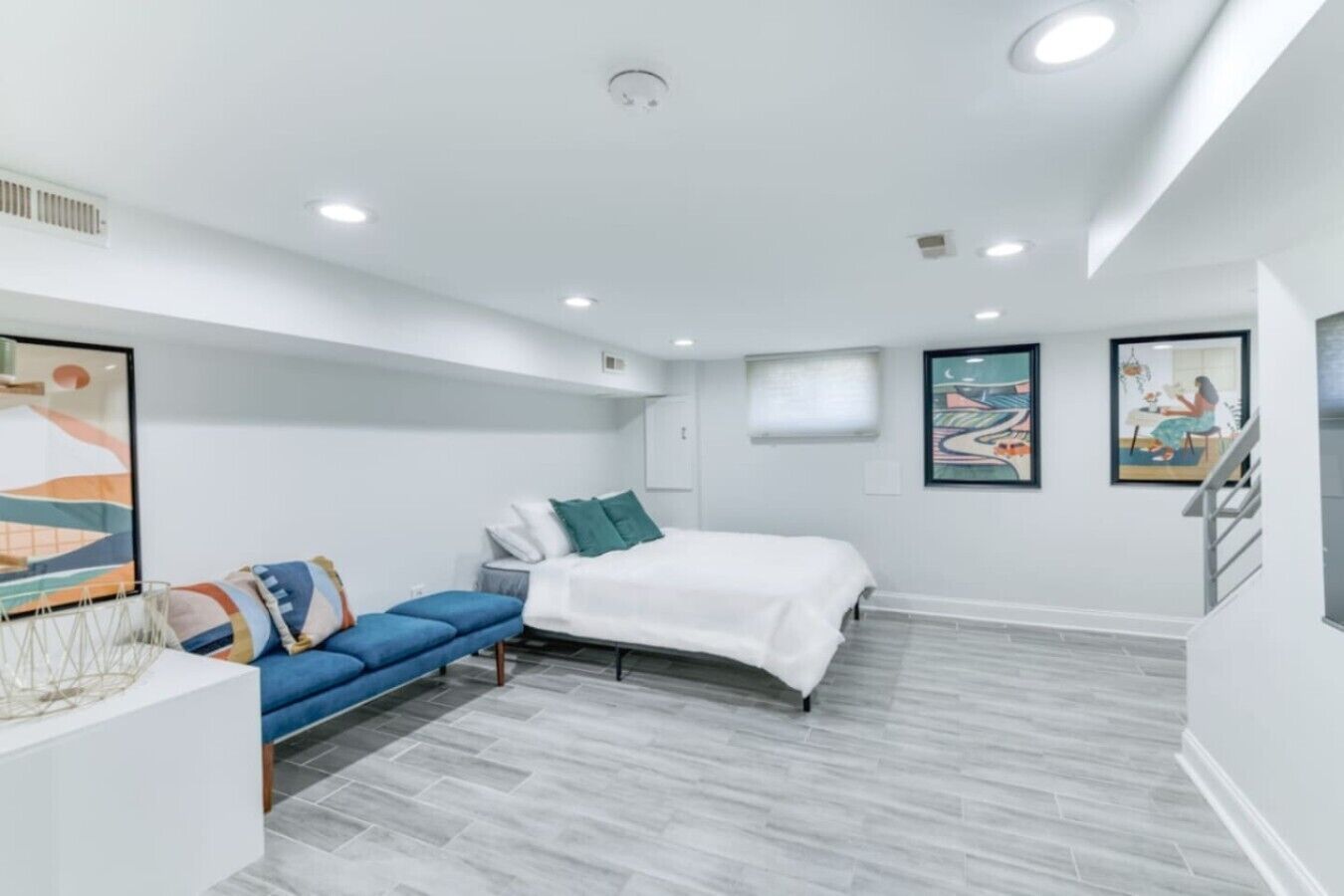 A modern bedroom with a bed, a blue sofa, and artwork on the walls.