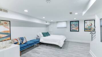 A modern bedroom with a bed, a blue sofa, and artwork on the walls.