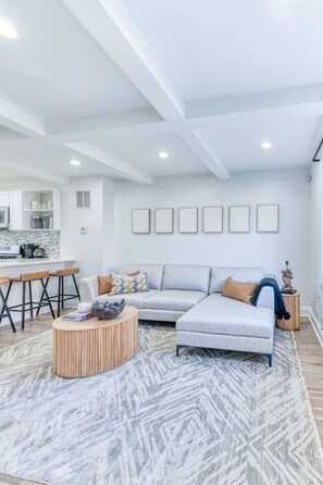 A modern living room with a sectional sofa, a round coffee table, and a patterned rug. - Group-Friendly DC Stay | 3BR + Free Street Parking (Washington)