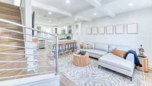 Een moderne woonkamer met een grijze modulaire bank, een ronde salontafel, en een trap naar een hoger gelegen verdieping.