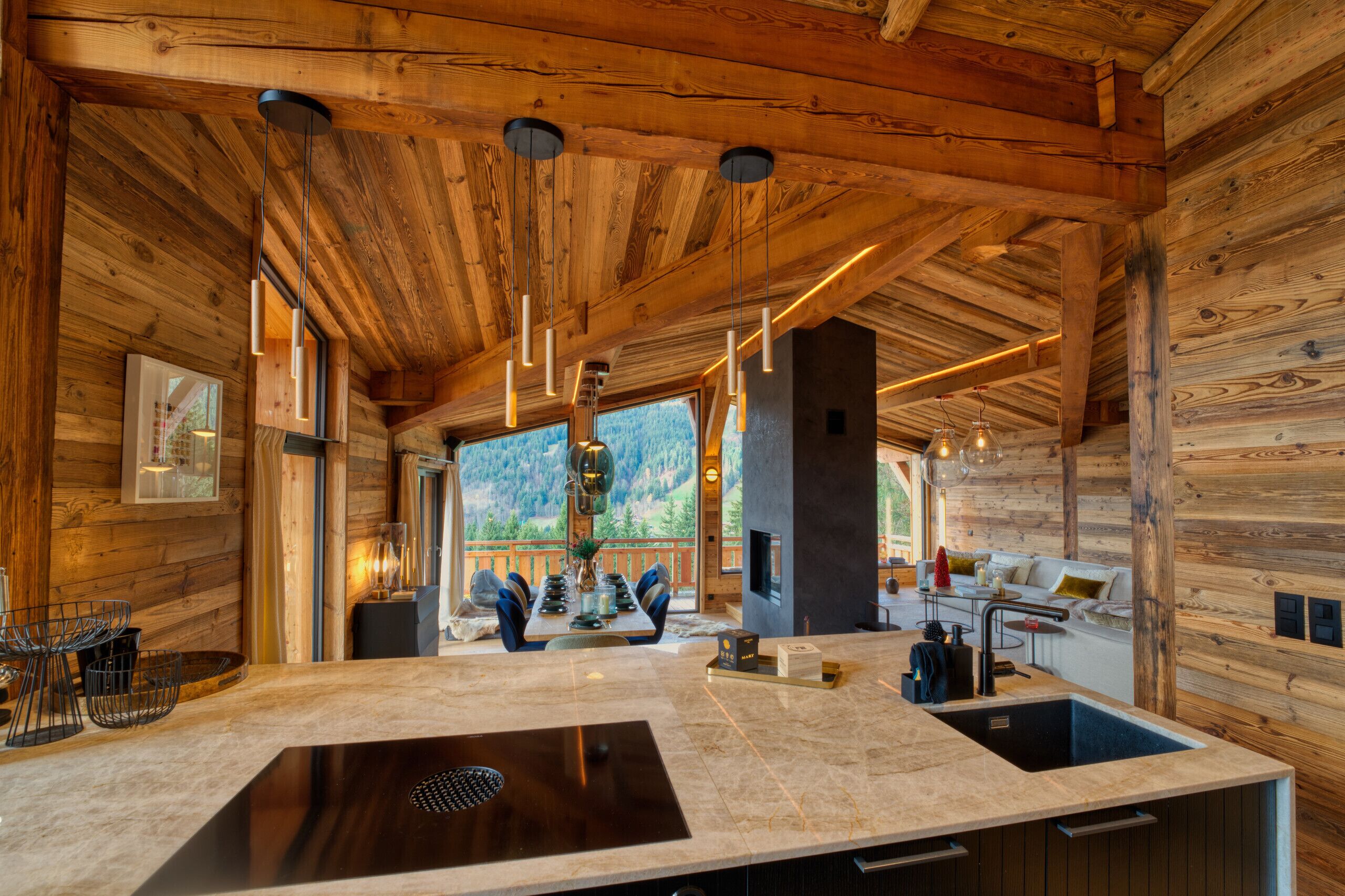 Una cucina moderna con un'isola grande, pareti in legno e illuminazione a sospensione.