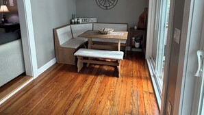 Una habitación acogedora con un banco de madera, una mesa y una lámpara fijada a la pared.