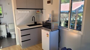 Una cocina compacta con microondas integrado, un lavabo y un refrigerador pequeño.