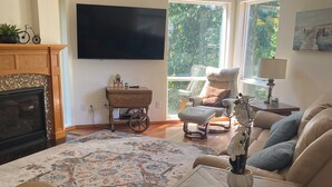 Ein Wohnzimmer mit Kamin, großem Fernseher, einer Couch und einem Couchtisch.