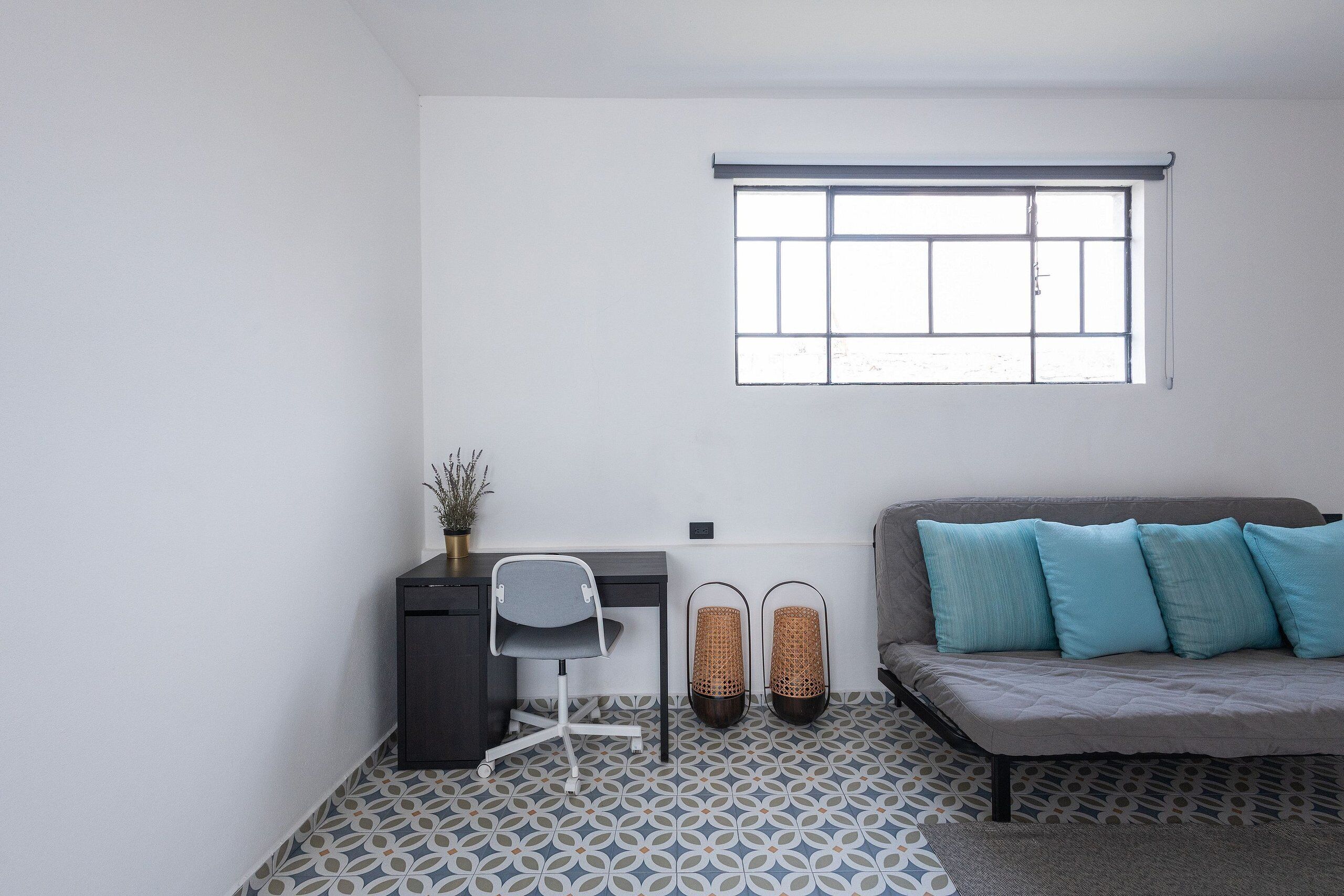 Une pièce comprenant un lit, un bureau, une chaise et une fenêtre.