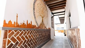 A corridor with a decorative wall featuring a cityscape silhouette and a large tree sculpture.