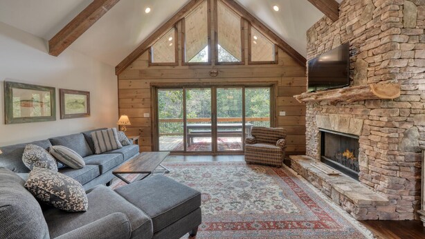A cozy living room with a stone fireplace, a large sofa, and a patterned rug. - Kenny's Place, Suches (Suches)