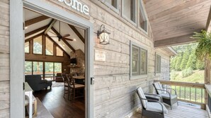 A wooden cabin with a covered porch, a dining area with a table and chairs, and a sign reading "KENNYS PLACE". - Kenny's Place, Suches (Suches)