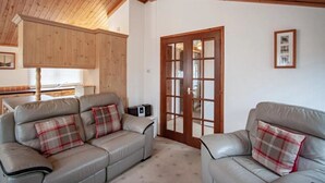 A cozy living room with two grey leather sofas, wooden cabinets, and a wooden ceiling. - A lodge that sleeps 4 guests  in 2 bedrooms (Windermere)
